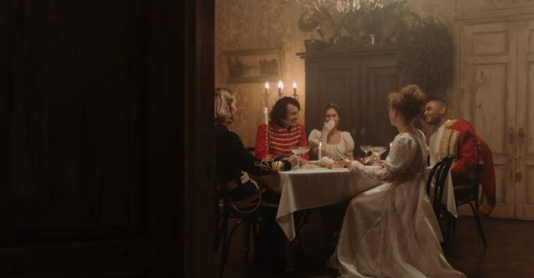 Reenactments - Group of Men and Women in Costumes Sitting by the Table