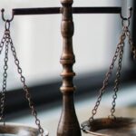 Authors - Decorative judgement scale and gavel placed on desk in light lawyer office against window