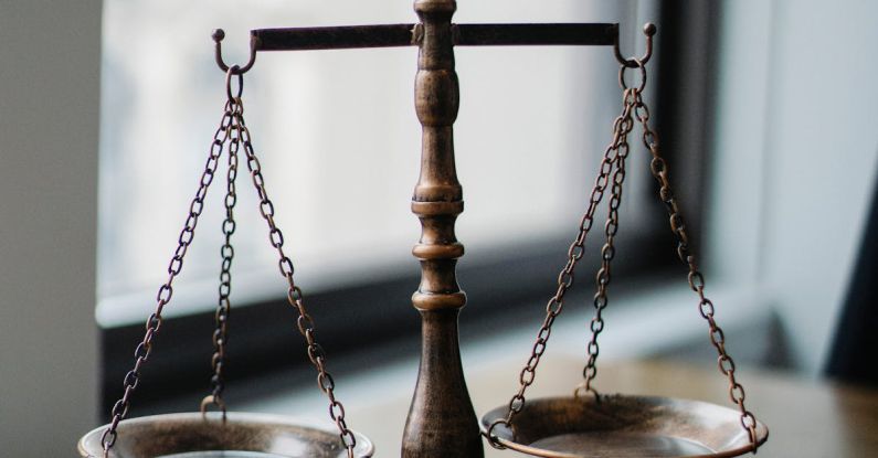 Authors - Decorative judgement scale and gavel placed on desk in light lawyer office against window